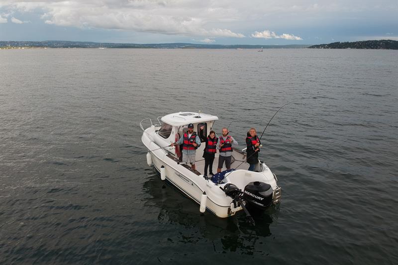 folk med fiskestang på en båt i fjorden
