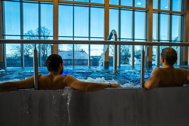 To personer i et boblebad med store panoramavinduer i bakgrunnen