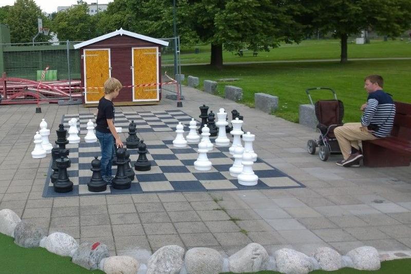 Two persons playing chess on a large board.