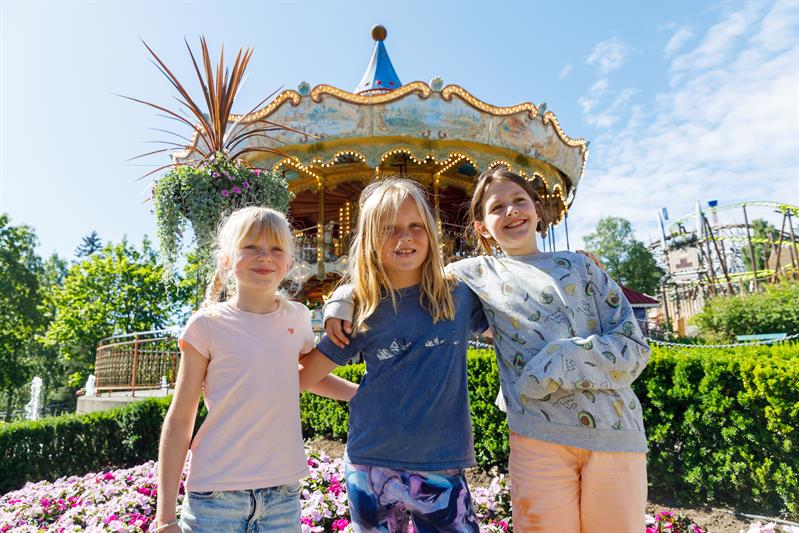 Three children standing in front of a carousel