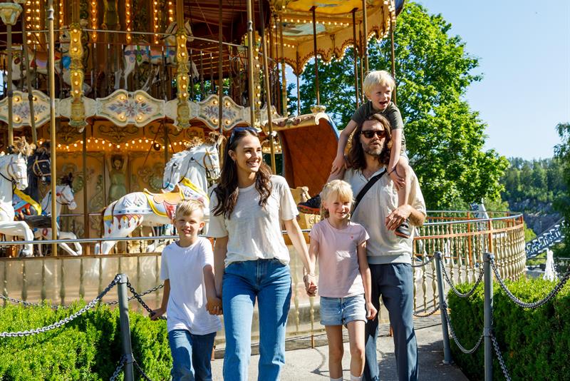 A family of five walking in front of a carousel